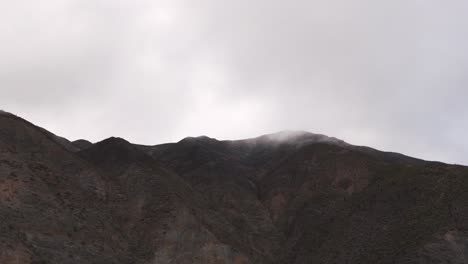 Drone-shot-near-mountain-top-surrounded-by-clouds