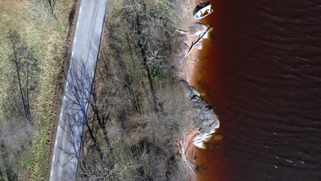 AERIAL---Road-and-lakeshore-in-Bohuslan,-Sweden,-wide-spinning-rising-shot