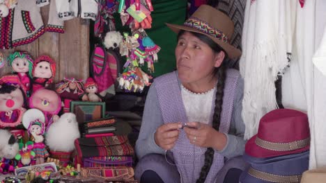 medium shot of traditional woman (cholita) weaving in the recoleta market, sucre