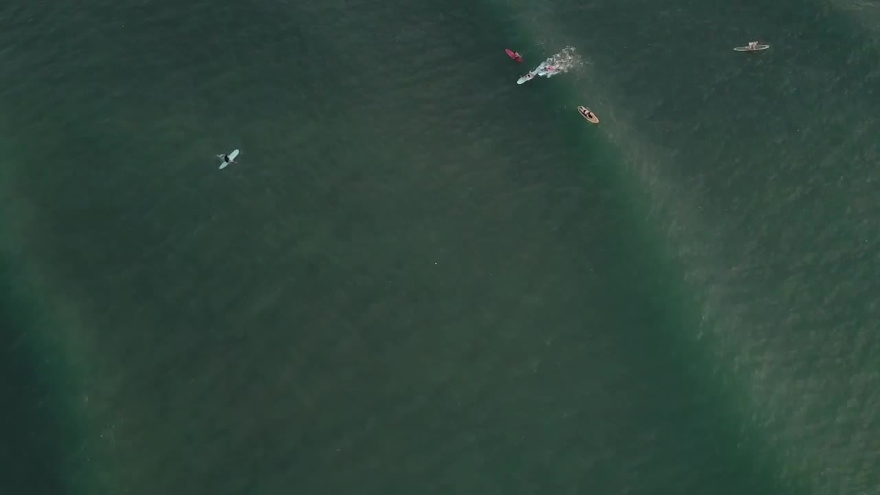 해변에서 서퍼 위에 일몰에 공중 무인 항공기