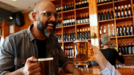 amigos brindando un vaso de cerveza en el mostrador en el bar 4k