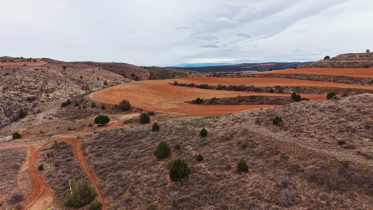 Uitzicht op glooiende heuvels en paden in een landelijk landschap bij bewolkt weer