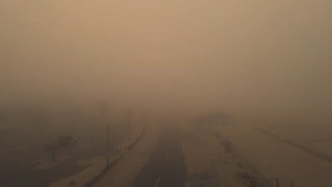 a construction vehicle enters in the foreground and drives off into the descending mist