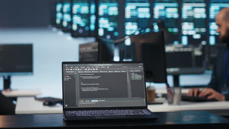 Focus on laptop used by expert in data center running code in blurry background