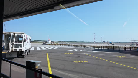 airport tarmac with planes and ground vehicles under clear blue skies, daytime view