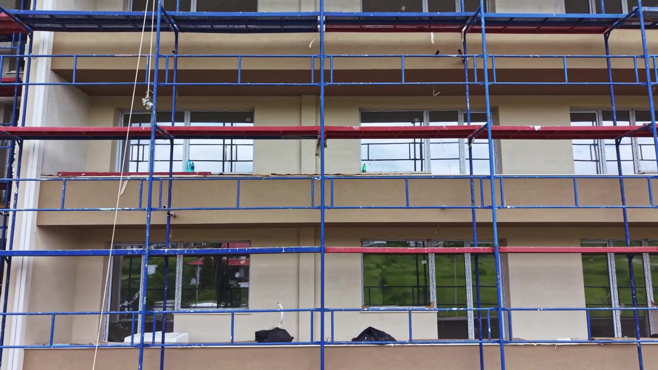 Facadeopdatering med stilladsværktøj. Detaljer om bygningsfacaderenovering, der involverer reparationsarbejde. Byggeprojekt med fokus på forbedring af ydermure og opsætning af stillads.