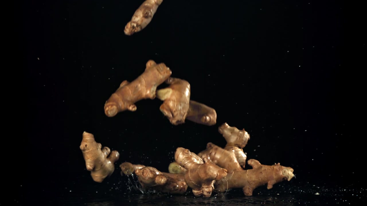 Fresh Ginger Roots Falling in Slow Motion onto a Black Background