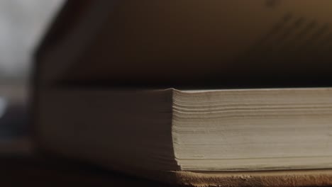 close-up view of a person’s fingers opening and flipping through the pages of an old or well-used book in a naturally lit indoor setting