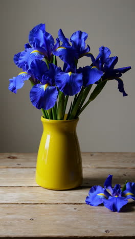 blue irises in a yellow vase on a wooden table
