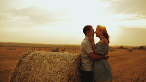 couple on harvested field. happy couple sitting on round bales of hay in summer