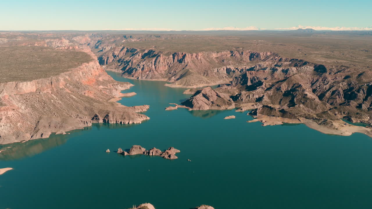 Cañón del Atuel near San Rafael, Mendoza, Argentina, showing turquoise waters flowing through dramatic reddish rock canyons under clear skies, drone slow pan