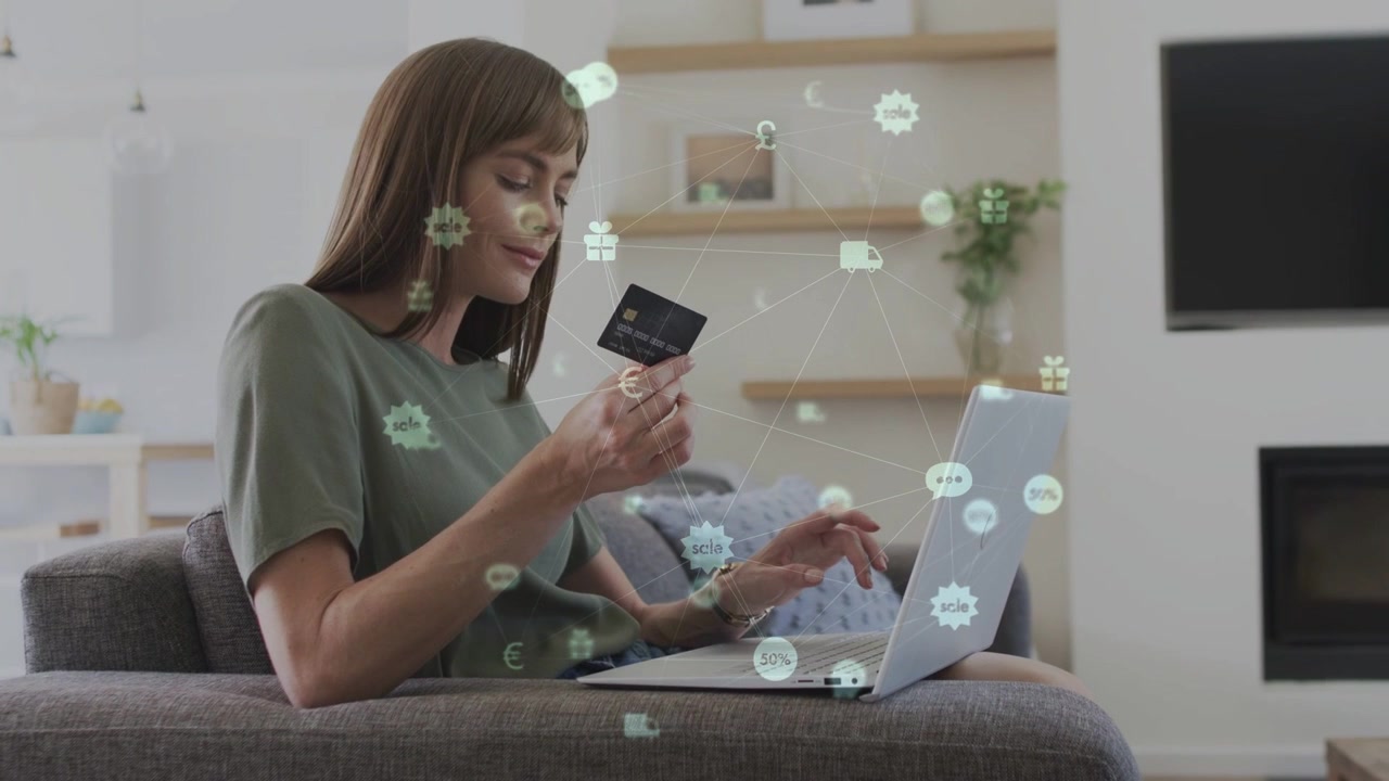 Mujer de mediana edad sosteniendo tarjeta y escribiendo en laptop, iniciando iconos financieros y completando compra.