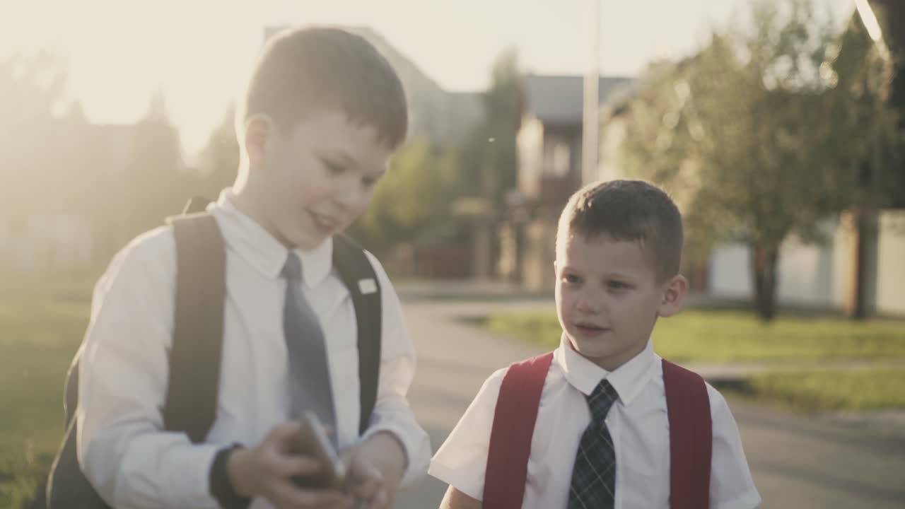 두 명의 학생들이 학교를 마치고 집에 가서 이야기를 나누고 손에 스마트폰을 들고 있습니다.