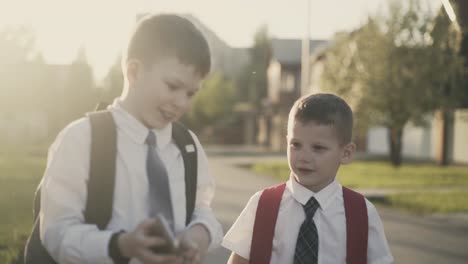 Cu-Rastreando-A-Dos-Escolares-Que-Van-A-Casa-Después-De-La-Escuela,-Hablan,-Tienen-Un-Teléfono-Inteligente-En-Sus-Manos