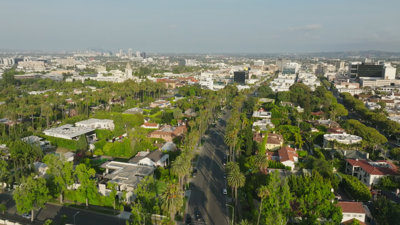 Volo con drone sopra un quartiere lussureggiante e alberato di Beverly Hills di giorno, con il cielo davanti e gli alberi sotto