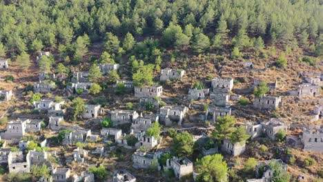 Breiter-Luftschuss,-Der-An-Einem-Sommertag-Um-Verlassene-Gebäude-In-Ruine-Im-Berühmten-Griechischen-Dorf-Kayakoy-Im-Wald-Eines-Berges-In-Fethiye,-Türkei,-Herumschwenkt