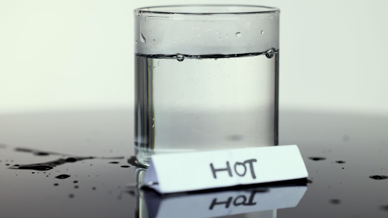 Hot water poured into clear glass, bubbles form, neutral background, steady camera, bright lighting