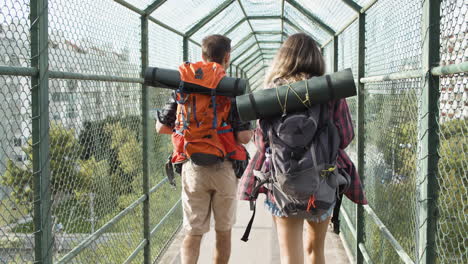 un par de mochileros caminando por un puente con vallas de seguridad