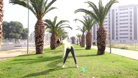 Mujer-Haciendo-Ejercicio-Sobre-El-Césped-En-La-Avenida-Rodeada-De-Palmeras