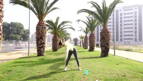 mujer haciendo ejercicio sobre el césped en la avenida rodeada de palmeras