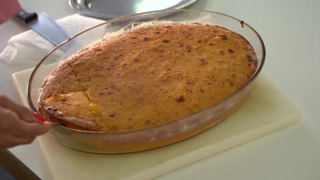 hands use fork and knife in getting a slice of hot salty cheesecake fresh from the oven - close up, high angle