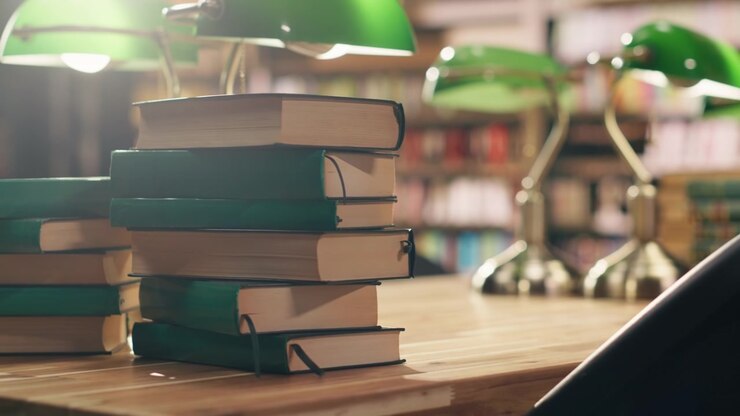 Primo piano di libri impilati su una scrivania in una tranquilla biblioteca universitaria con illuminazione calda