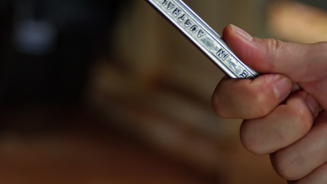 Close up of man spinning a spanner in his hand in a workshop, clip 3