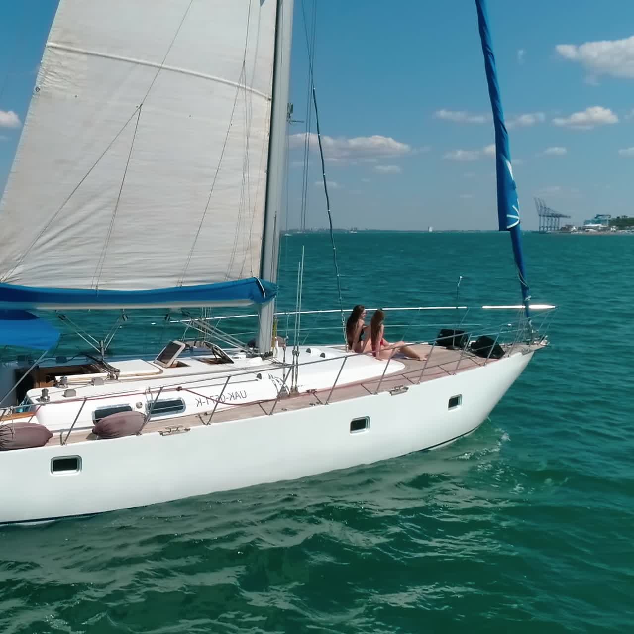 Beautiful white boat with sails on water. Modern yacht floating among many others on sea. People rest on a sea voyage during a sail ship in summer