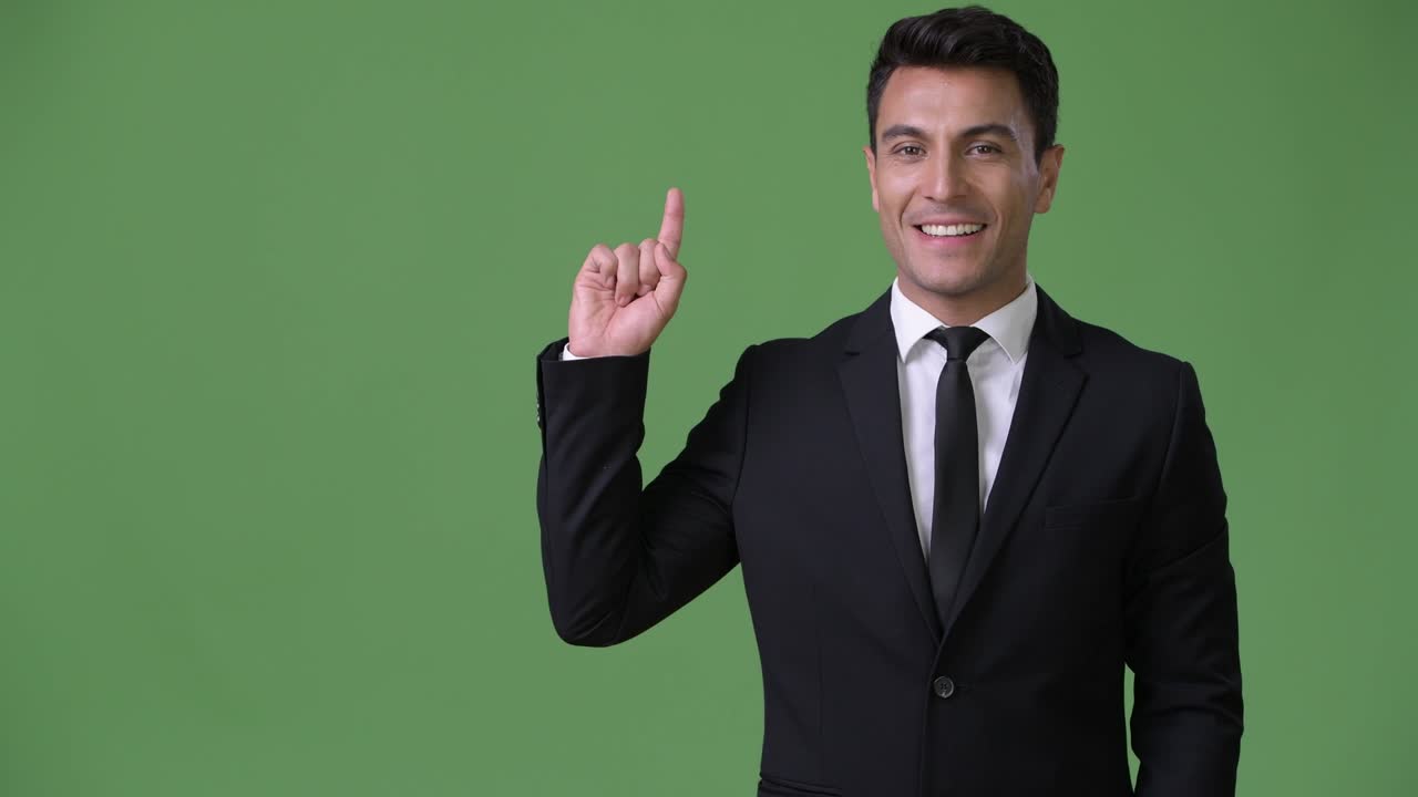 joven y guapo hombre de negocios hispano contra un fondo verde