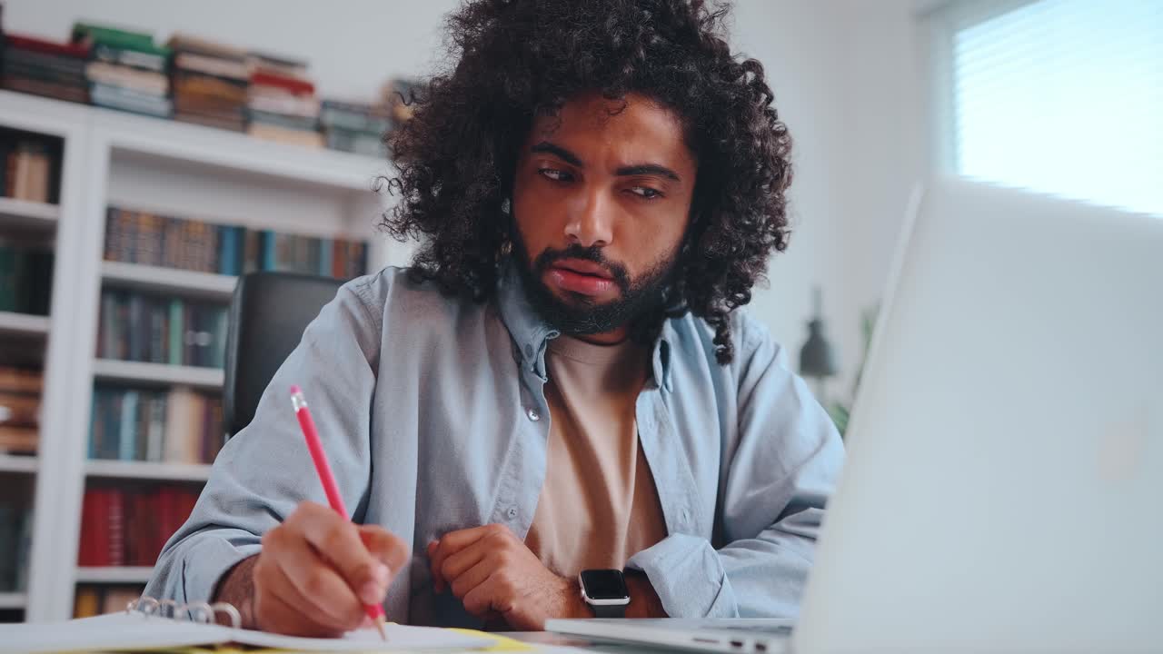 Arabian american student sits at table engages in distance learning using laptop