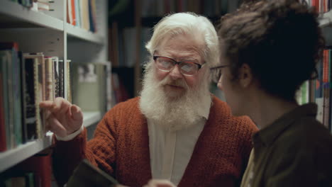 hombre anciano recomendando libros a un estudiante joven que visita la biblioteca