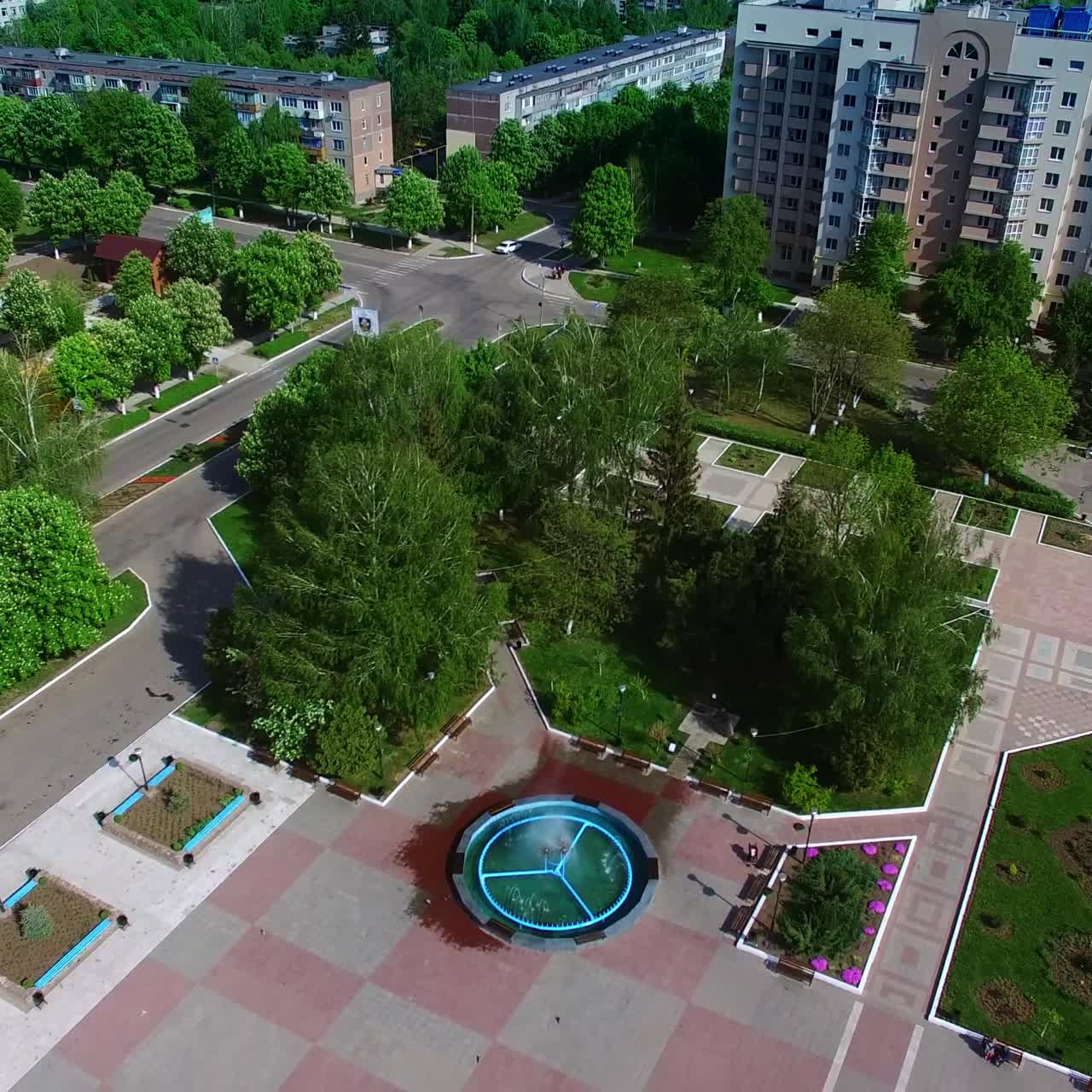 Provincial city panorama on sunny summer daytime. Drone footage over the multi-storied buildings, roads and city square. Top view