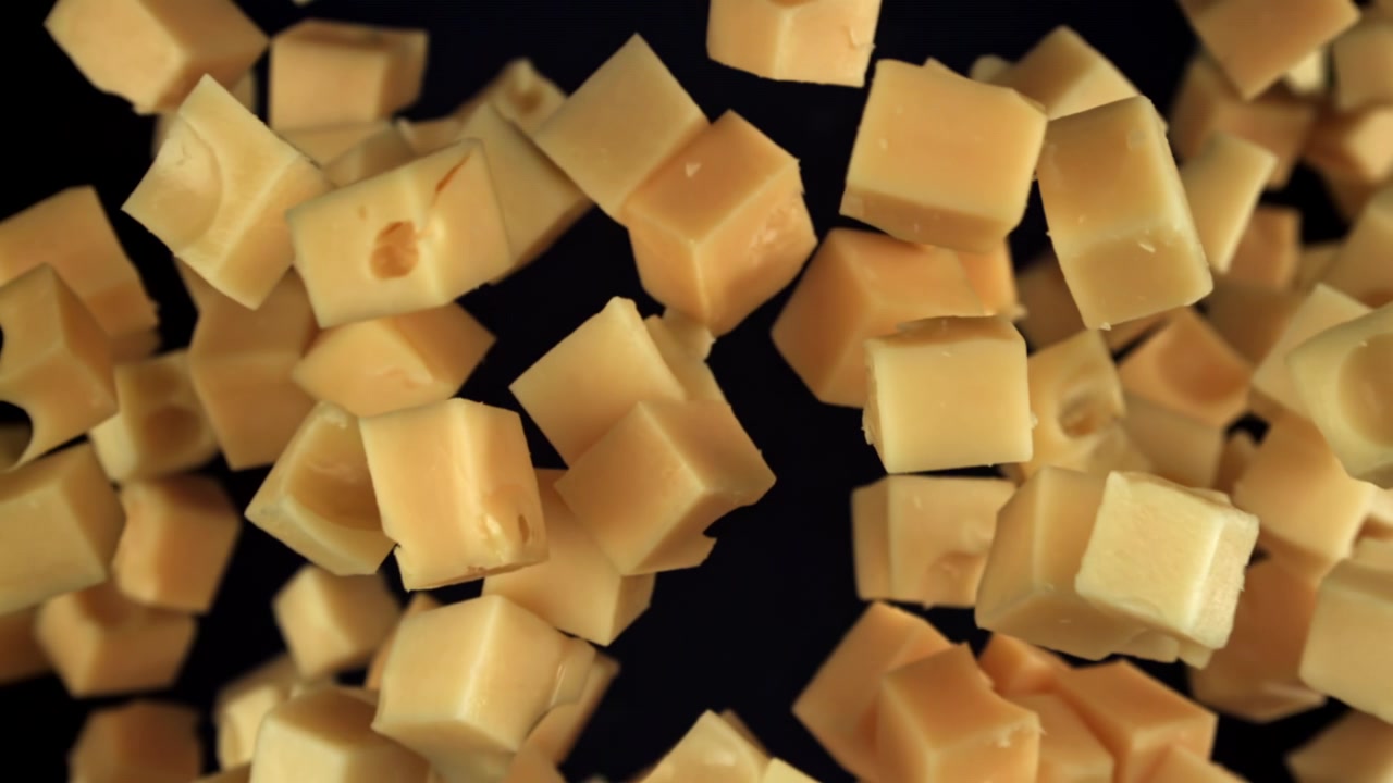 Cubes de fromage tombant au ralenti sur fond noir