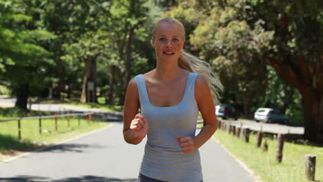 a smiling woman jogs towards the camera