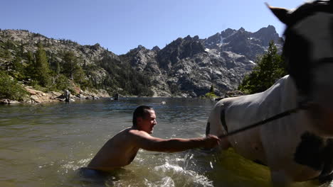 Un-Hombre-Tomando-Su-Caballo-Para-Nadar-En-Upper-Sardine-Lake-Debajo-De-La-Sierra-Buttes-En-Tahoe-National-Forest,-California