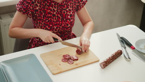 woman slicing sausage in kitchen