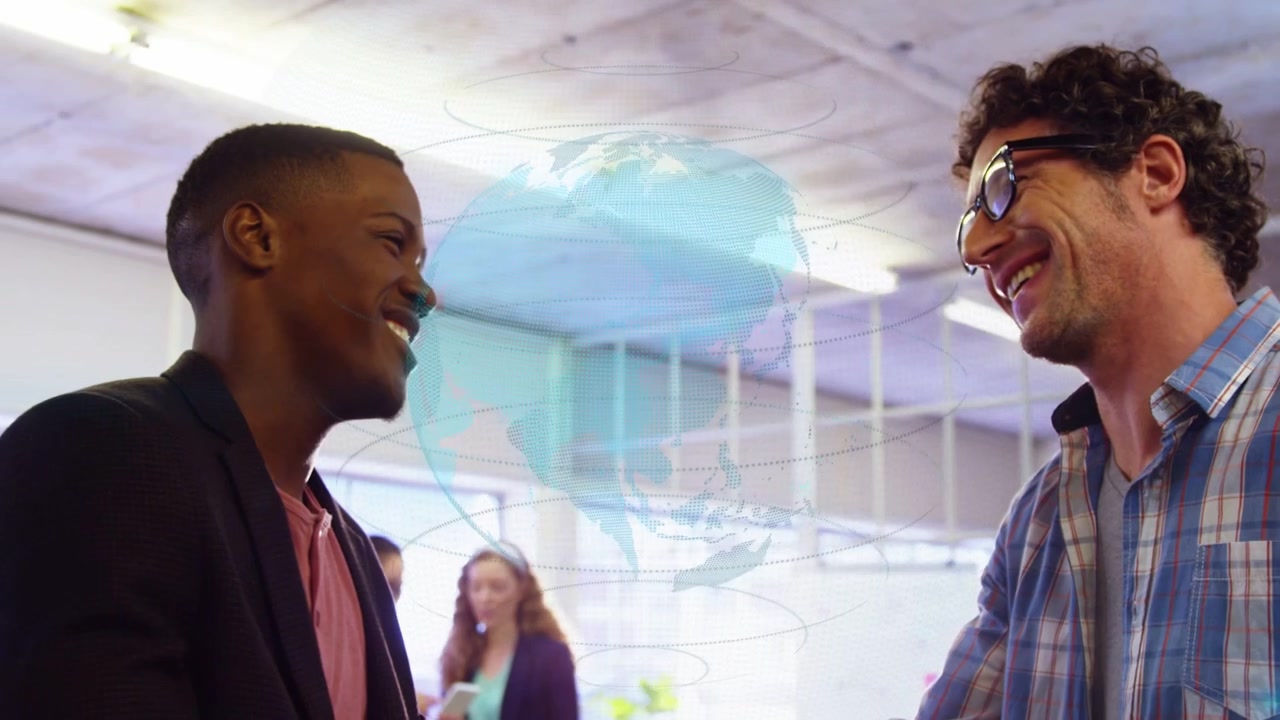 Men shaking hands in office, initiating camera pullback and globe overlay sealing business deal