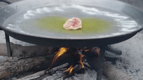 cooking chicken in a paella pan over a wood fire
