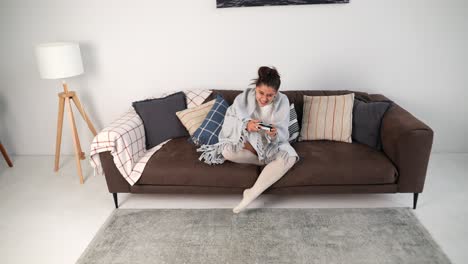 vrouw ontspant zich op een bank, speelt videospelletjes.
