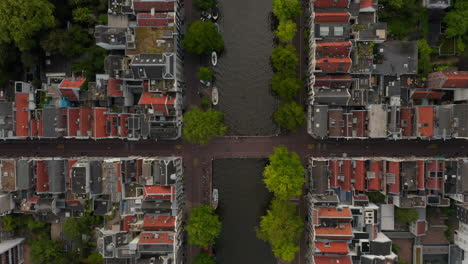 Amsterdam,-Holanda-Vista-Aérea-De-Los-Pájaros-Del-Canal-Con-Tráfico-De-Botes-Y-Tejados-De-Casas-Rojas