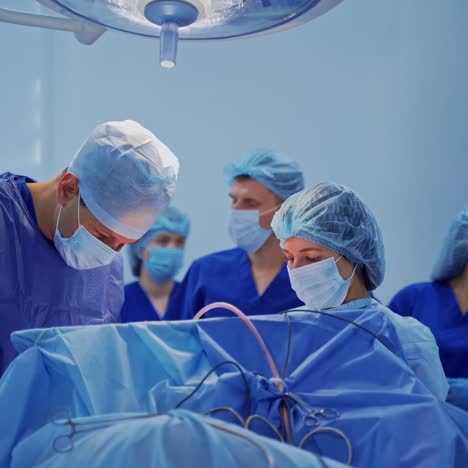 group of medical specialists in surgical room. doctors in blue uniform conduct a surgery under the medical lamp. health care concept.