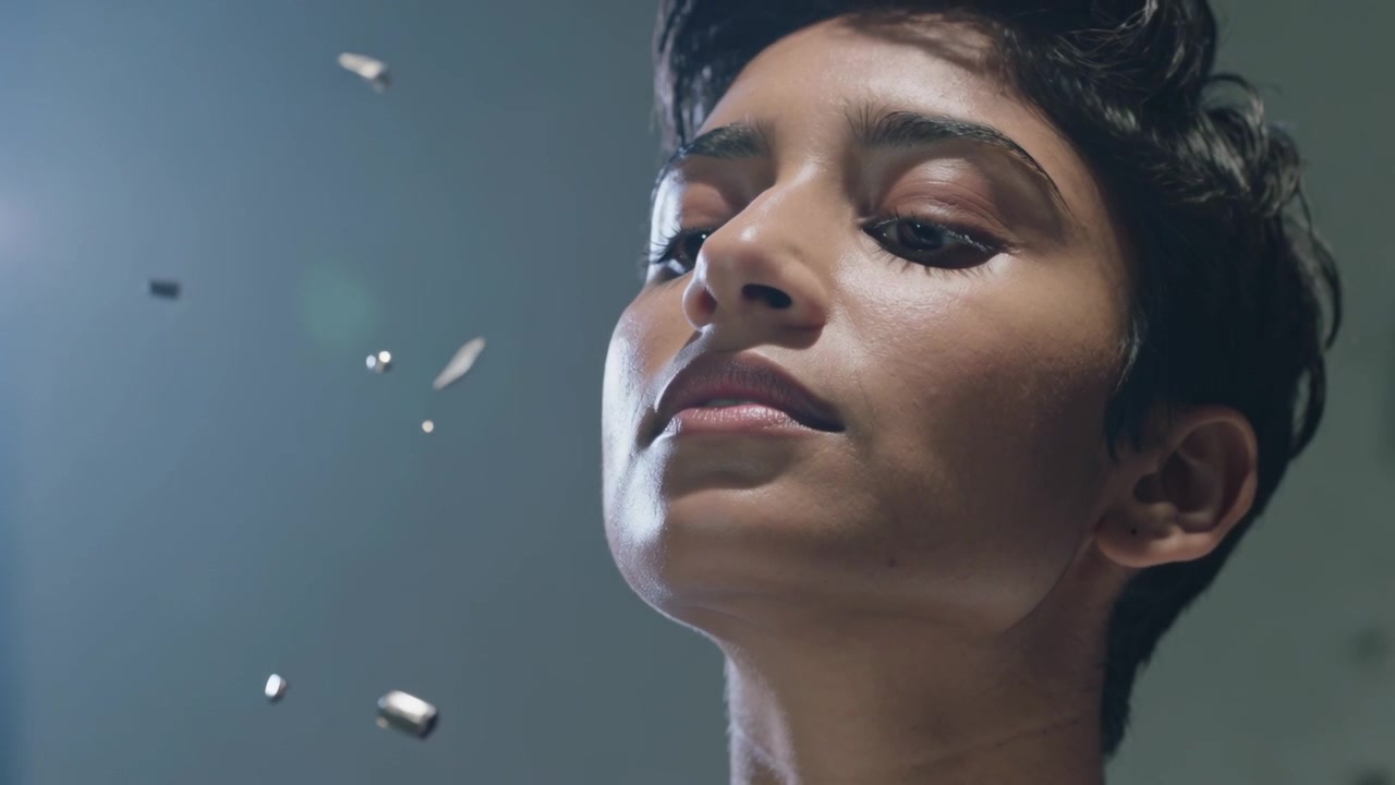 Observing fragments drifting near face, South Asian woman tilting head and tracking in studio light