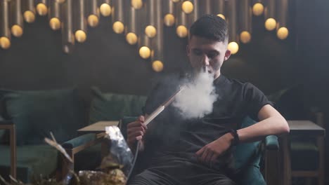 guy sitting on the couch and smoking hookah