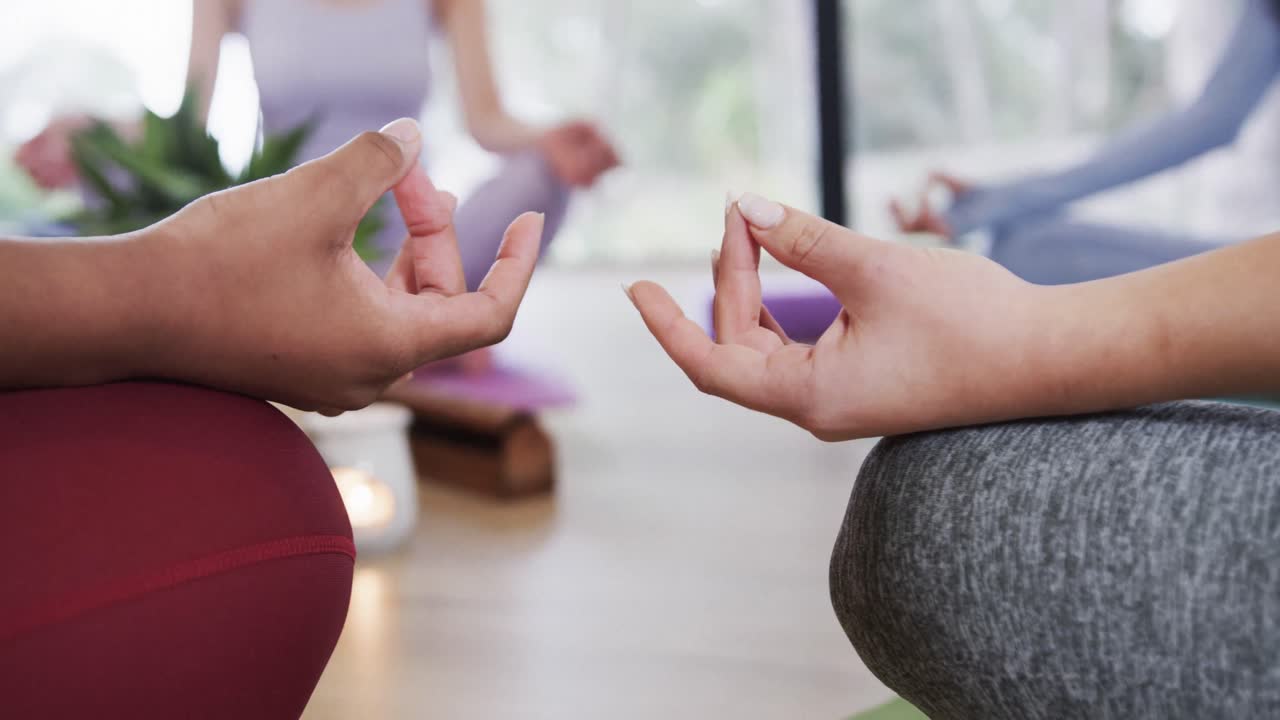 sección media de mujeres diversas con paciencia mudra meditando en el estudio de yoga