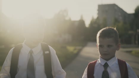 seguimiento de dos escolares van a casa después de la escuela hablan sonrisa abrazo 1 disparo contra el sol