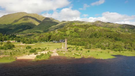 Aerial-Shot-Panning-Around-Glenfinnan-Monument,-To-Reveal-Glenfinnan-Viaduct-In-The-Scottish-Highlands