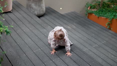 blondy cute toddler girl climbs up the big wooden staircase in slow motion