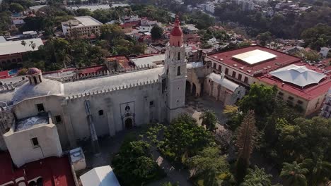 drone view flying alongside a historic church in cuernavaca city center, capturing the rich architecture and vibrant surroundings