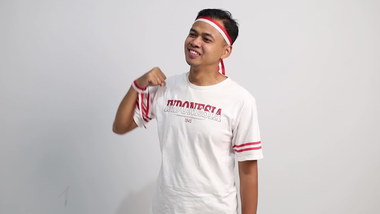 Handsome Asian man giving salute to sideways, celebrate Indonesian independence day on 17 August isolated over white background