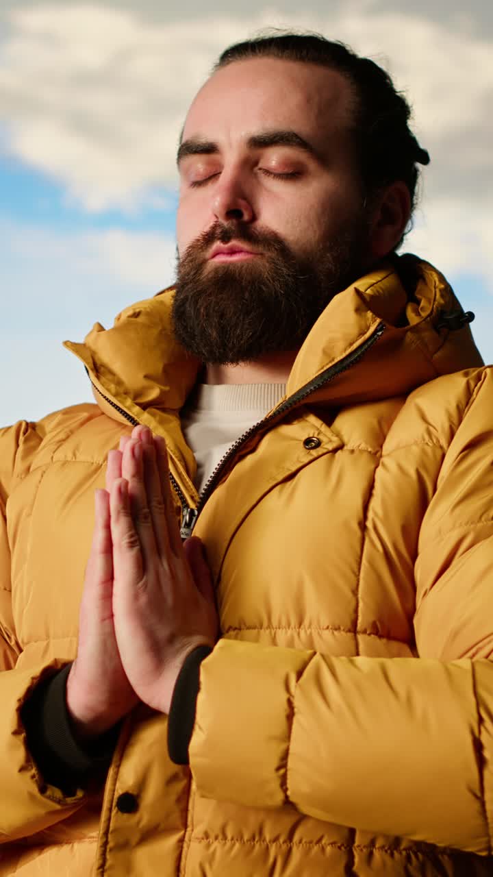 Homem barbudo meditando ao ar livre com as mãos em posição de oração